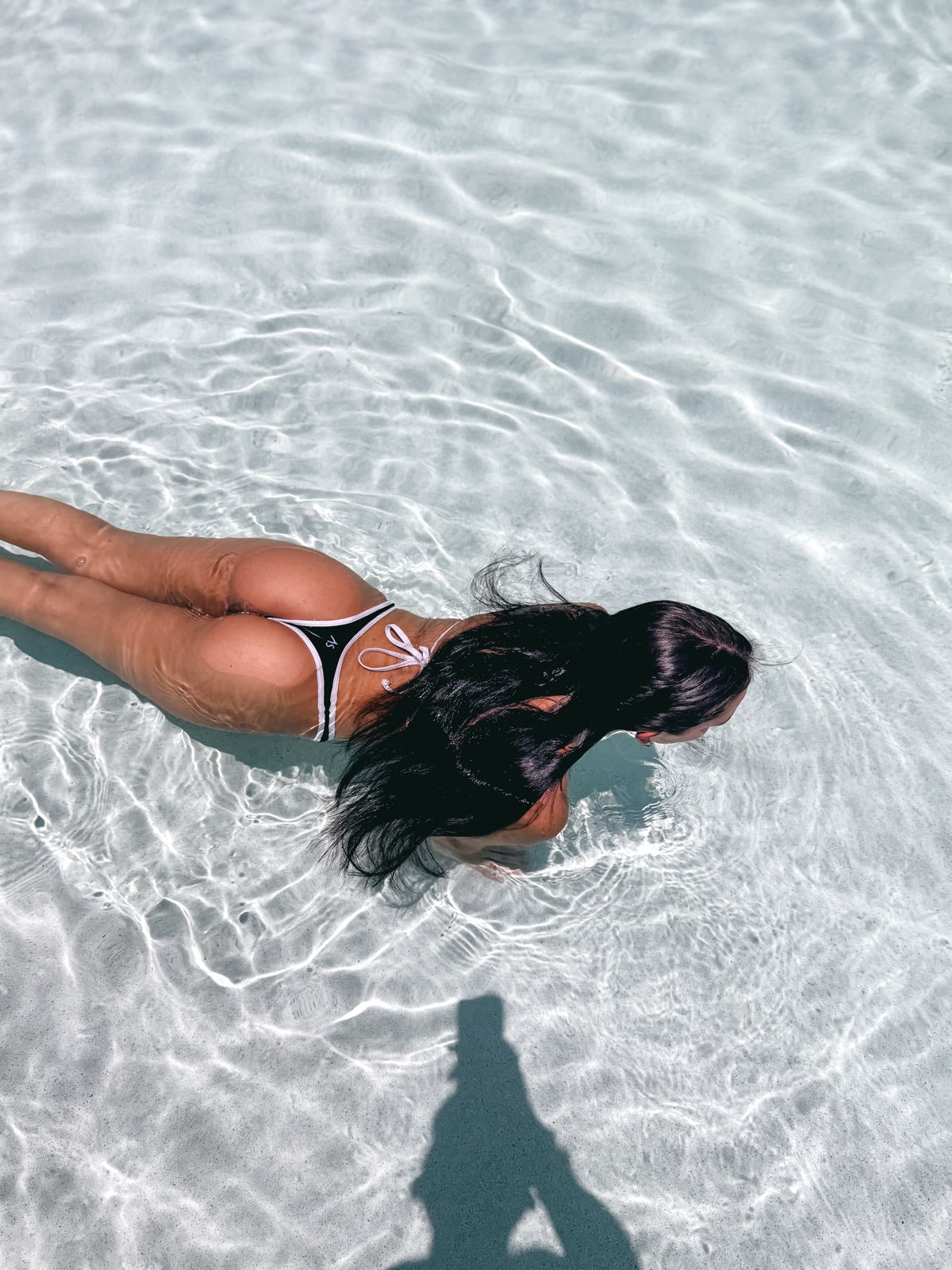 Overhead view of model in black Audi Swim thong bikini in crystal clear tropical ocean water — Cancun spring break 2026