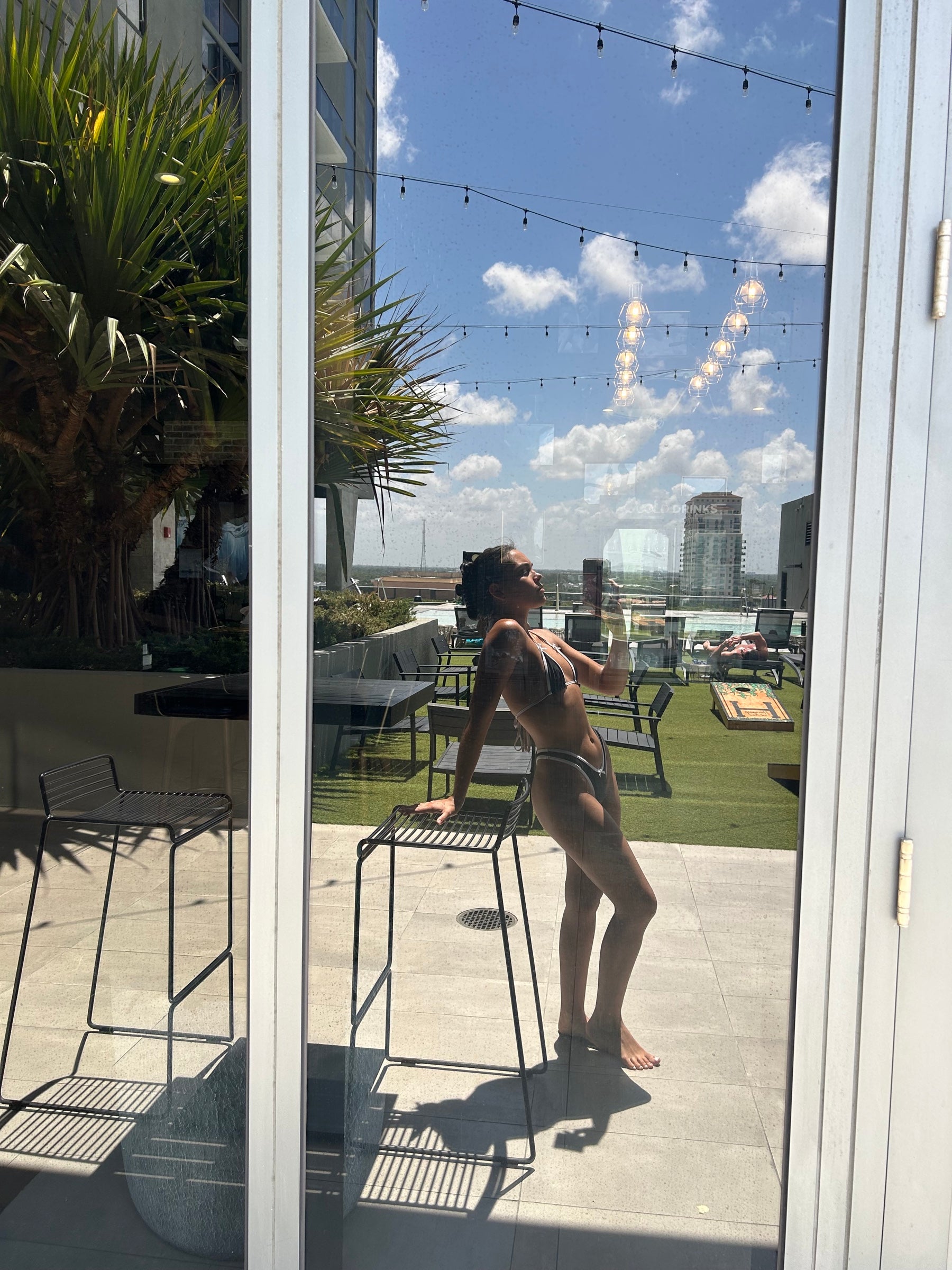 Rooftop pool party bikini outfit for Ultra Miami 2026 festival — black contrast Bow Babe set with city skyline and string lights